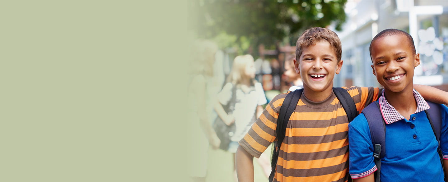 Two boys wearing backpacks smiling.