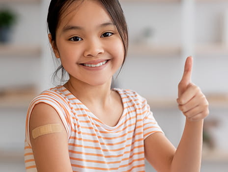 Smiling child with a bandaid giving a thumbs up