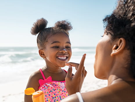 Mother applying sunscreen to daughter