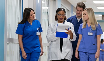 Physician consulting with nurses in hospital hallway.