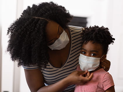 Mom putting mask on child.