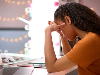 young girl with head in hands sitting at a desk